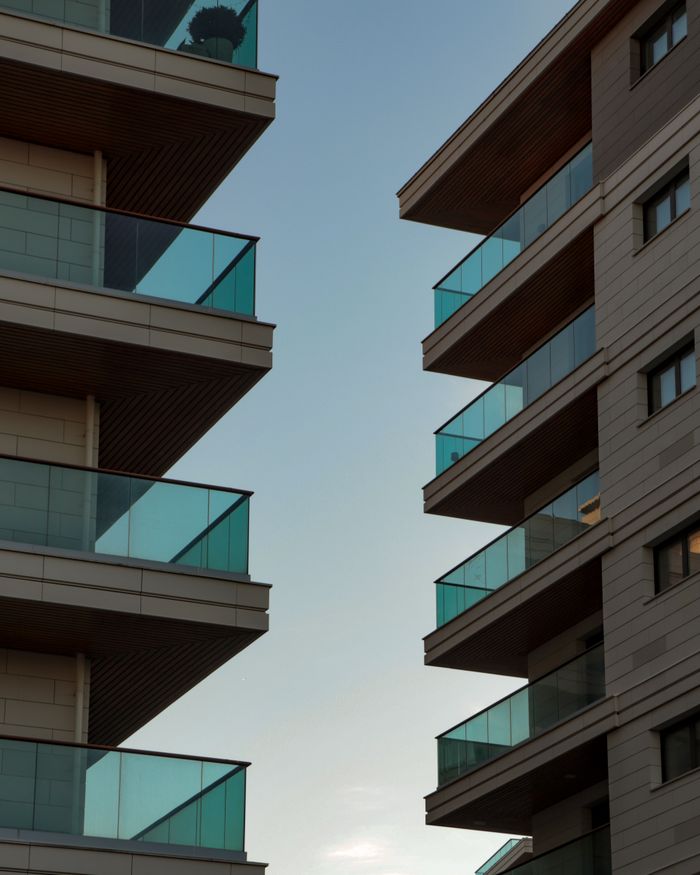 A view of modern apartment buildings with glass balconies against a clear sky backdrop.
