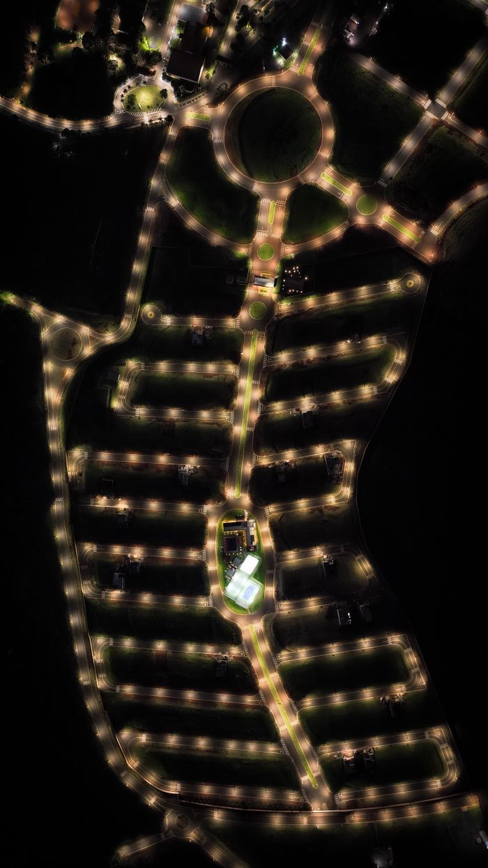 Dark aerial view highlighting a residential layout illuminated by streetlights at night.
